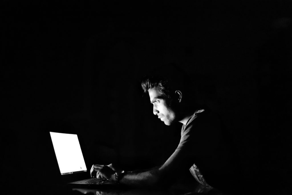 a hacker works on a laptop in darkness
