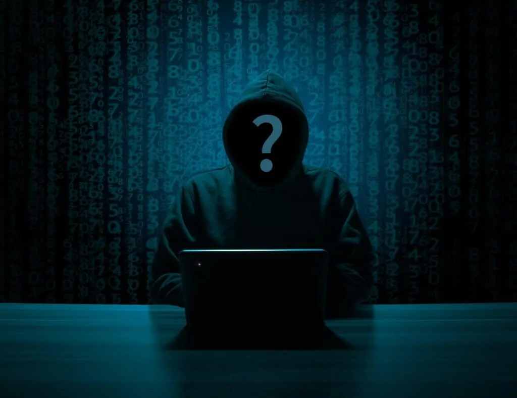 hacker on laptop in darkened room